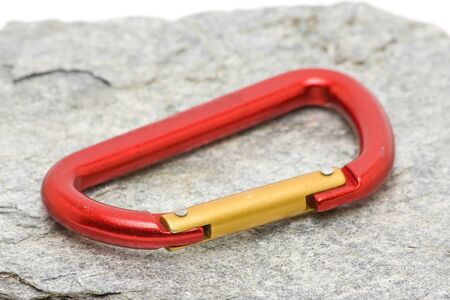 Single red climbing carabiner on grey rockの写真素材
