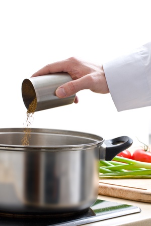 Male chef seasoning meal in pot over white backgroundの写真素材