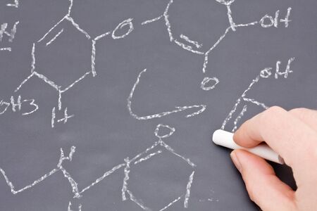 Researcher or teacher writing chemical formula on chalkboardの写真素材