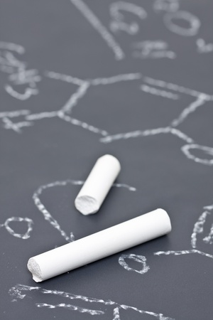 Two pieces of chalk on chalkboard with chemical formulaの写真素材