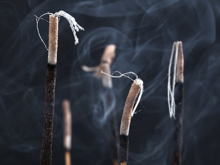 Close up of burning incense sticks with smoke over black backgroundの写真素材