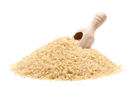 Raw dried couscous with wooden scoop isolated on white background