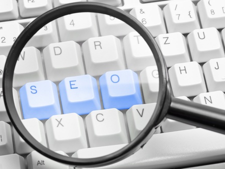 SEO - search engine optimization concept with the letters s, e, o on a computer keyboard seen through a magnifying glassの写真素材