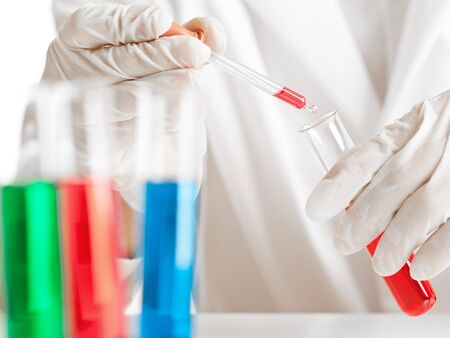 Test tubes with various chemicals with researcher in the backgroundの写真素材