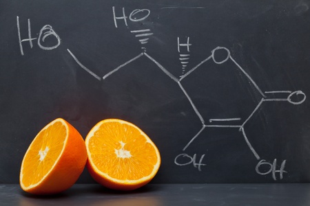 Structural formula of vitamin C on blackboard with orange Structural formula of vitamin C on blackboard with orange