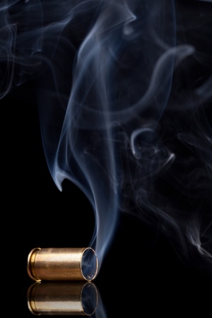 Smoking 9mm bullet casing over black backgroundの写真素材