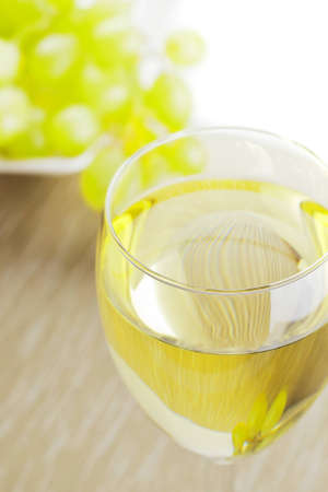 Glass of white wine with grapes in the backgroundの写真素材