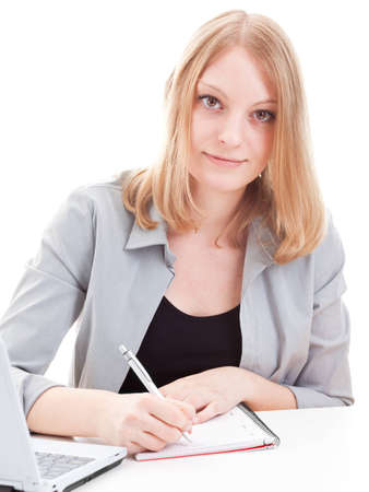 Young attractive woman taking notes in front of laptop isolated on white backgroundの写真素材