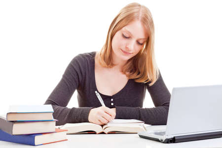 Young attractive female student taking notes from open book isolated on white backgroundの写真素材