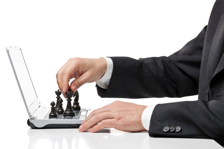Businessman with chess figures on laptop keyboard - strategy or management conceptの写真素材