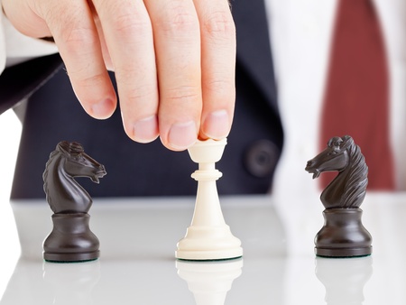 Business man holding chess queen figure between two arguing knight figures - conflict management conceptの写真素材