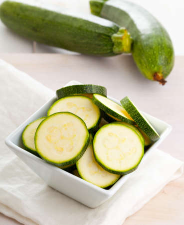 Fresh organic zucchini sliced in bowl on wooden tableの写真素材