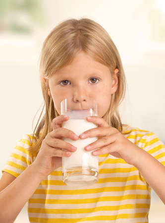 Cute young girl drinking a glass of milkの写真素材