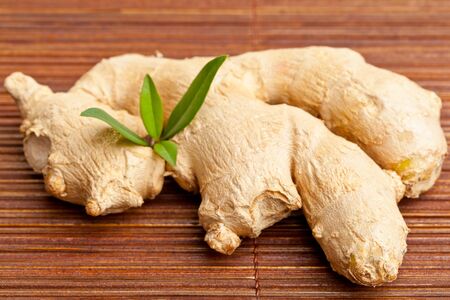 Whole fresh ginger root on bamboo matの写真素材