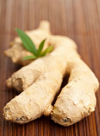 Whole fresh ginger root on bamboo matの写真素材