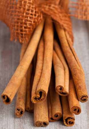 Bundled dried cinnamon sticks on wooden backgroundの写真素材