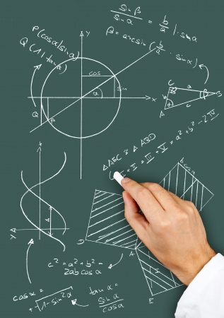 Research scientist writing maths diagrams and formulas with chalk on blackboardの写真素材