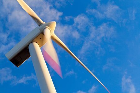 Windmill power generator at sunset with blue skyの写真素材