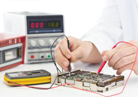Electronics engineer testing computer part in electronics workshopの写真素材