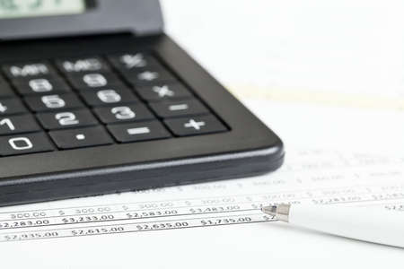 Calculator with pen on paper sheets with numbers - finance expenses or budget conceptの写真素材