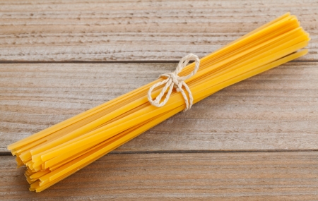 Bundled dried tagliatelle pasta on wooden tableの写真素材