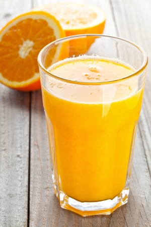 Glass of freshly pressed orange juice with sliced orange half on wooden tableの写真素材