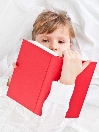 Girl on bed reading book - education or knowledge conceptの写真素材