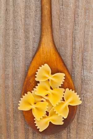 Italian farfalle pasta on wooden spoon on wooden tableの写真素材