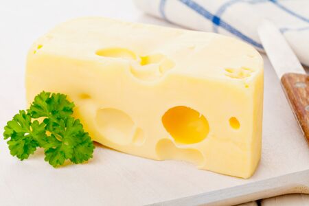 Piece of fresh organic edam cheese on wooden board on breakfast kitchen tableの写真素材