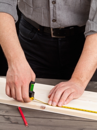 Young man measuring wooden plank - diy or home renovation conceptの写真素材