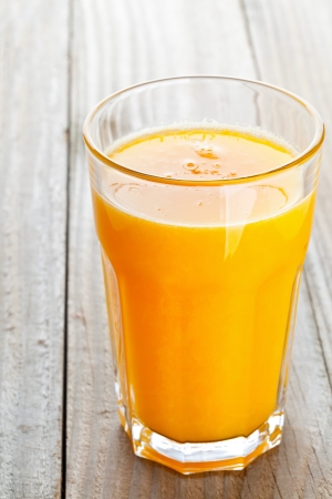 Glass of freshly pressed orange juice on wooden tableの写真素材