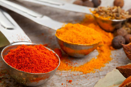 Various mixed spices  oregano, curcuma, paprika, anise  in metal scoops on wooden tableの写真素材