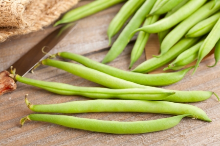 Organic pole beans in paper bag on wooden tableの写真素材
