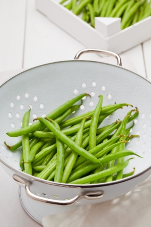 Organic pole beans in white strainer on kitchen tableの写真素材
