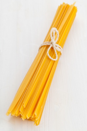 Bundled dried tagliatelle pasta on wooden tableの写真素材