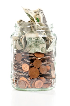 Open penny jar with bank notes over white backgroundの写真素材