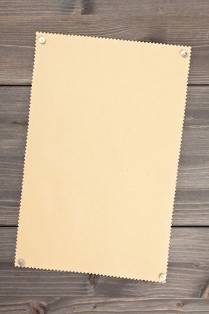 Empty brown vintage paper with pushpins on wooden backgroundの写真素材