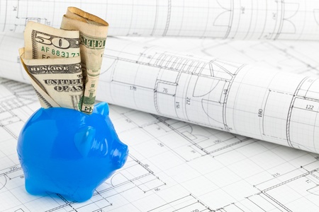 Blue piggybank with dollar bills on home construction plans - home building financing conceptの写真素材