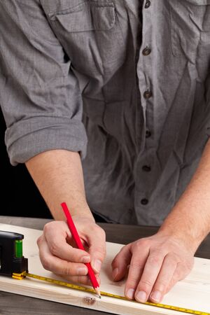 Young man measuring wooden plank - diy or home renovation conceptの写真素材