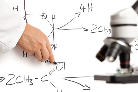 Teacher or scientist explaining chemical process on whiteboard with microscope in front