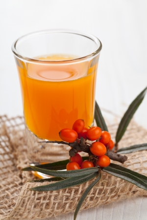 Sallow-thorn liqueur wit sallow-thorn berries on white wooden tableの写真素材