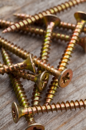 Pile of screws with shallow depth of field on old wooden plankの写真素材