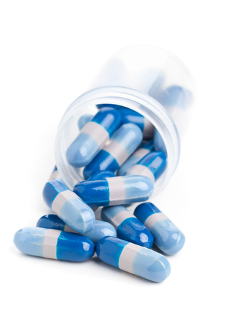 Blue pills in transparent pill bottle on white の写真素材
