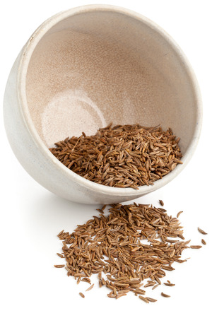 Dried caraway or cumin seeds in small bowl on white backgroundの写真素材