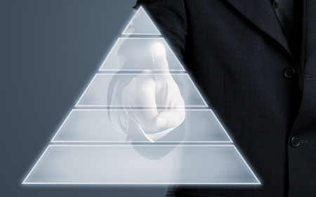 Businessman touching pyramid infogram graphics on virtual touchscreen with copy spaceの写真素材