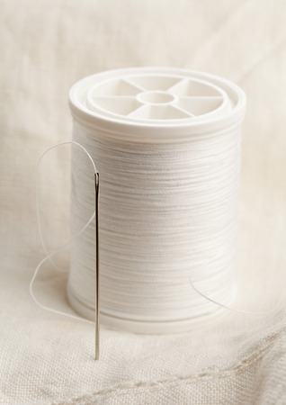Macro of sewing needle and thread on white fabricの写真素材