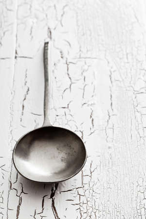 Old silver serving spoon on old white wooden table with copy spaceの写真素材