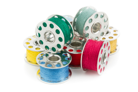 Colorful assortment of sewing yarn spools on white background close up viewの写真素材