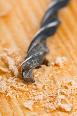 Wood drill on wooden plank with wood chips, selective focus on drill tip - home improvement, diy or woodworking conceptの写真素材