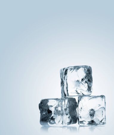 Heap of three ice cubes with reflection over blue background with copy spaceの写真素材